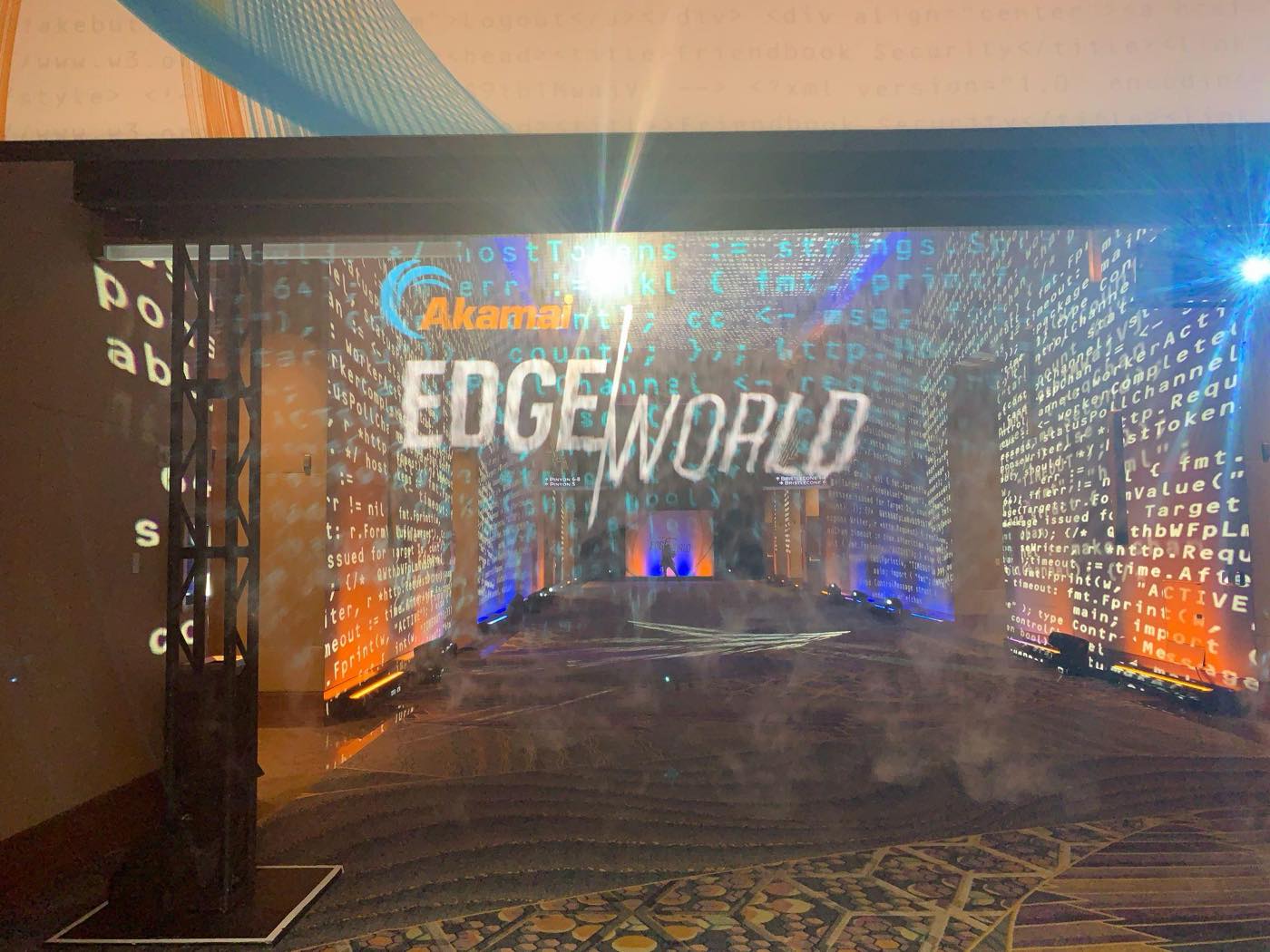 The Edge World main stage entrance onsite, with the Akamai Edge World logo projected in code across the walls through haze